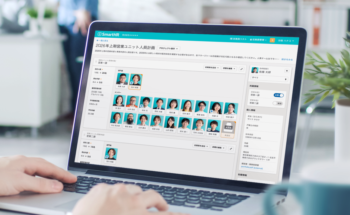 オフィスでパソコンを開き、SmartHRを使って人員配置を検討している写真